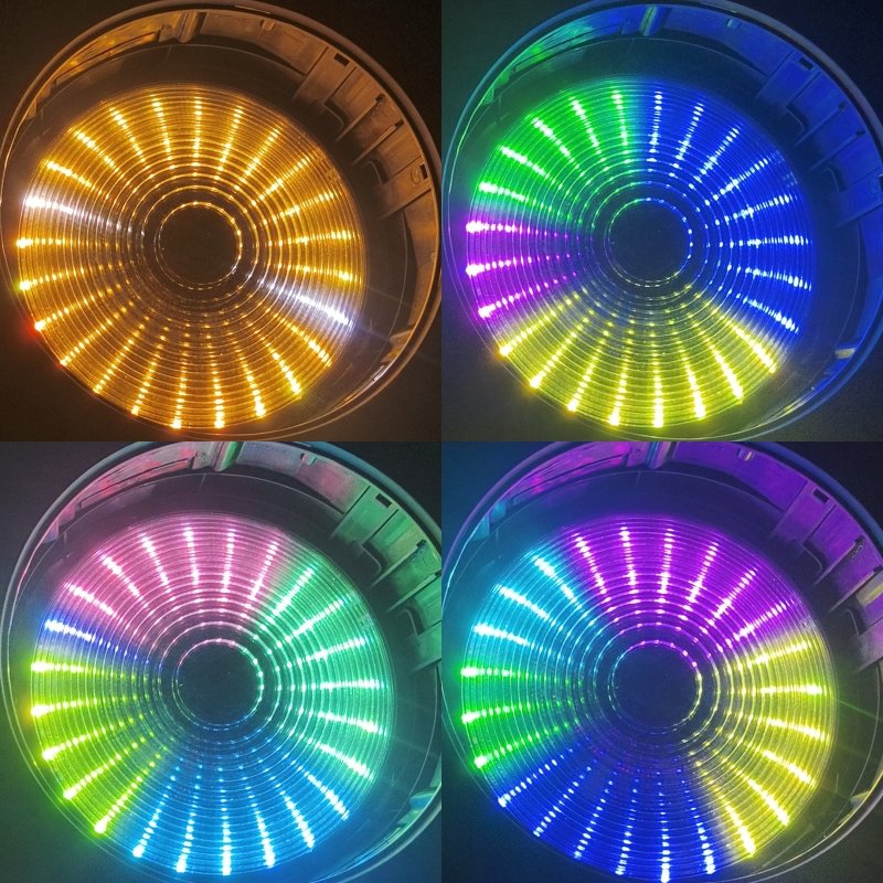 A grid of four circular LED lights, each displaying different colors—yellow, green-blue, pink-green, and blue-purple—with concentric rings and radial lines creating a vibrant, glowing effect reminiscent of the IP20 150W Moving Mac One lighting display.